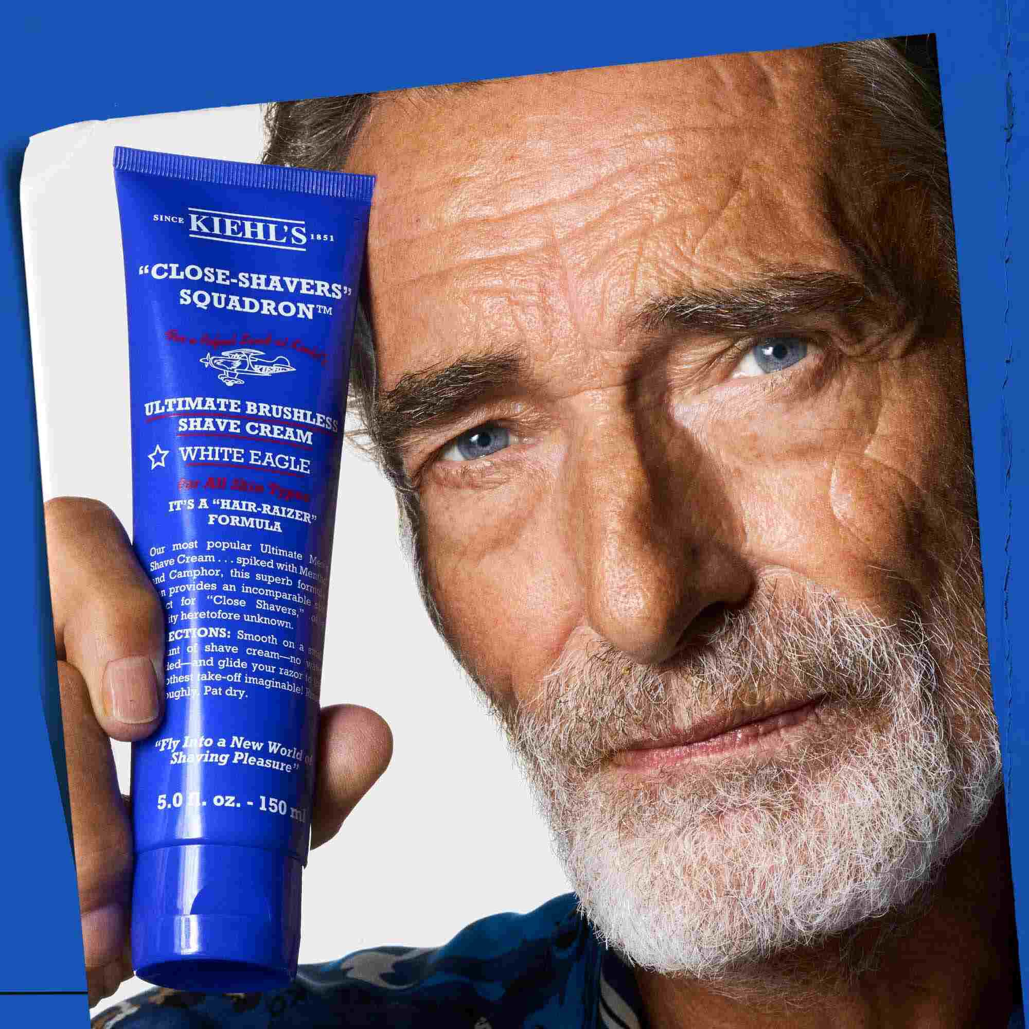A man holding a tube of Ultimate Brushless Shave Cream White Eagle.