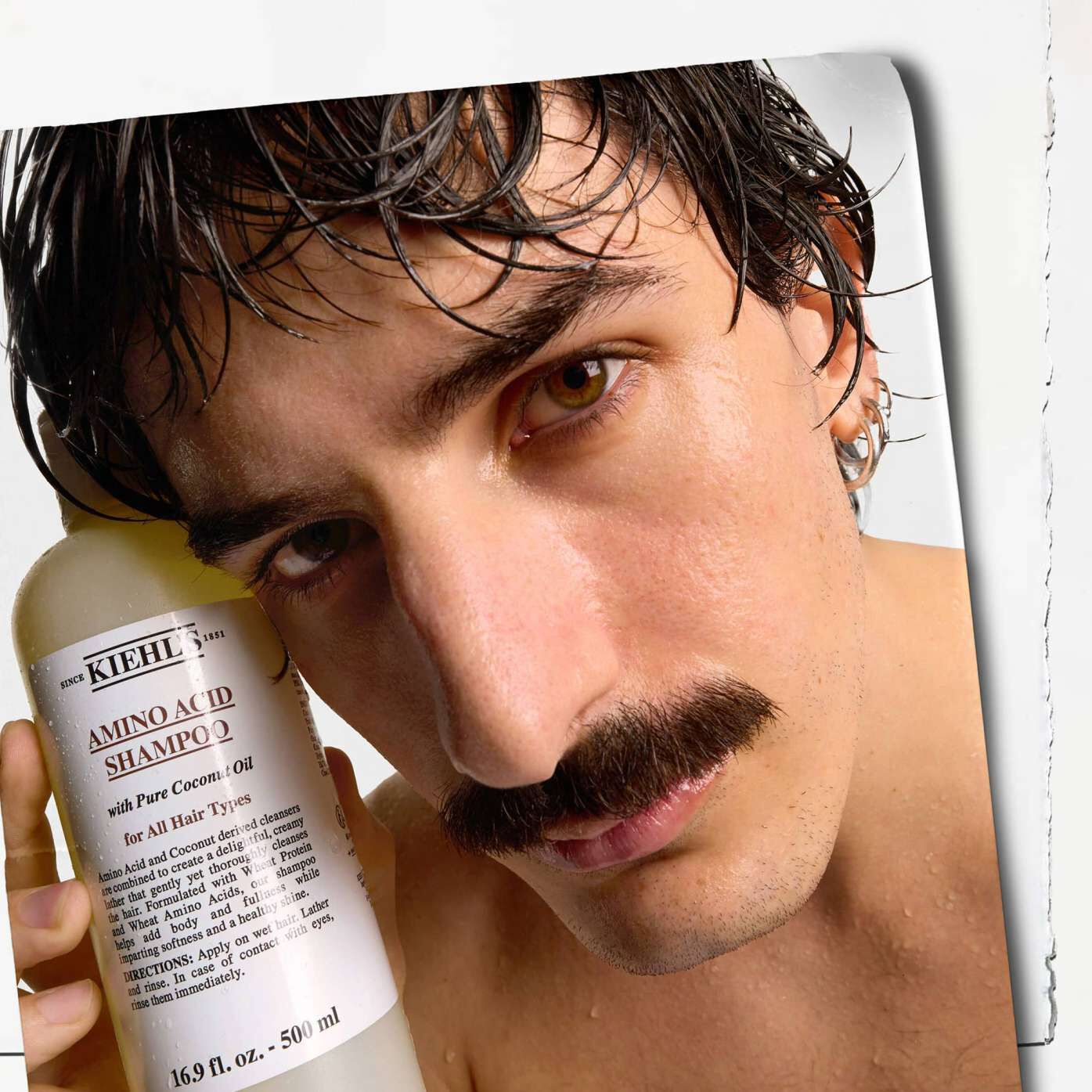 Model with a mustache and a bottle of Kiehl's Amino Acid Shampoo
