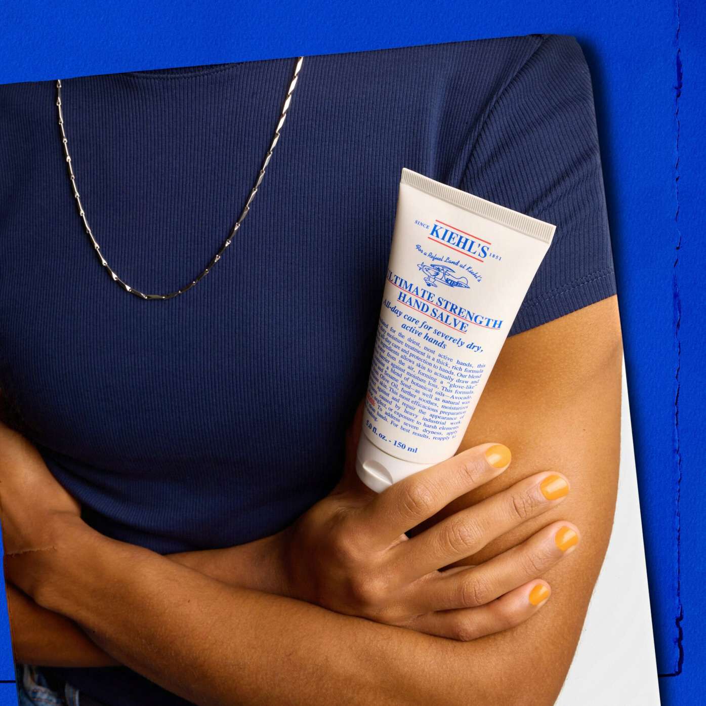 Model holding a tube of Kiehl's Ultimate Strength Hand Salve
