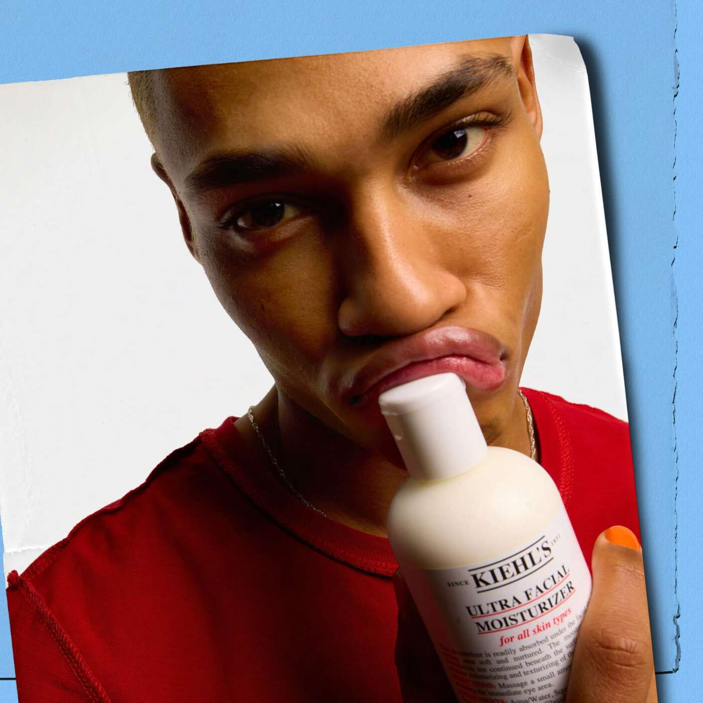 Model pressing a bottle of Kiehl's Ultra Facial Moisturizer into their lips