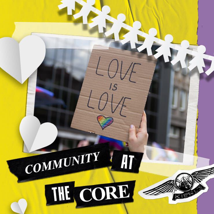 A person holds a sign reading "LOVE IS LOVE," surrounded by colorful decorations and heart shapes, promoting community and inclusion.