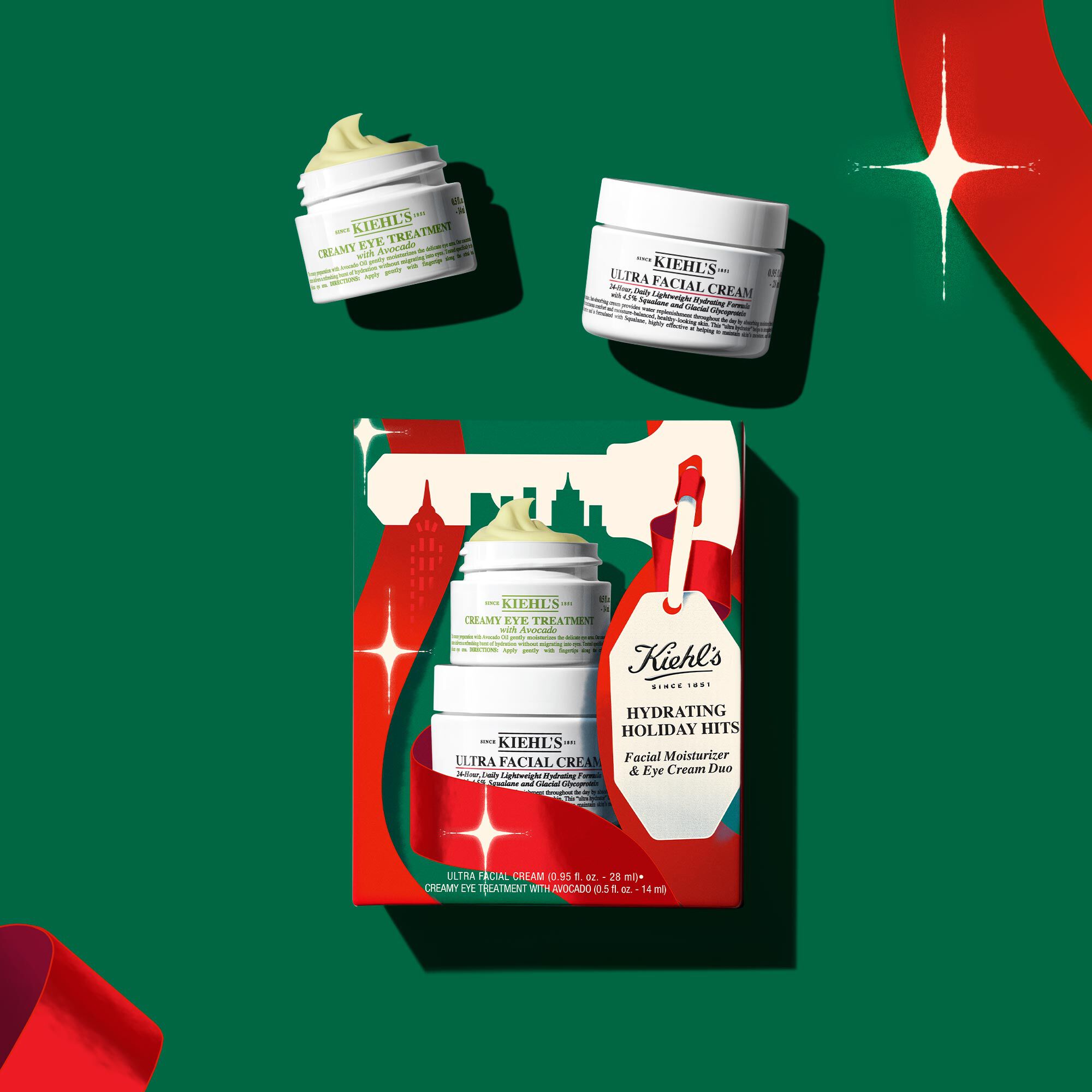 "Hydrating Holiday Hits" skincare gift set on a green background, featuring Ultra Facial Cream and Creamy Eye Treatment with Avocado in festive packaging.