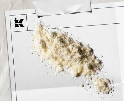 A pile of white powder on a blank sheet of paper with a logo in the corner, suggesting an artistic or stylistic presentation.