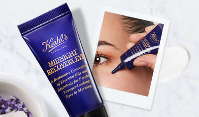 A tube of Kiehl's Midnight Recovery Eye cream is displayed next to an image of a person applying the product near their eye, highlighting its restorative features for youthful-looking skin.