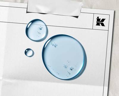 Two droplets of water on a blank sheet of paper featuring a black "K" logo and a piece of tape at the top.