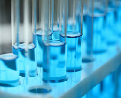 Close-up of a row of test tubes filled with a bright blue liquid, lined up in a test tube rack.