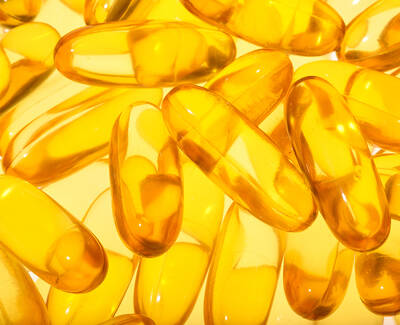 A close-up image of numerous transparent yellow gel capsules arranged closely together.