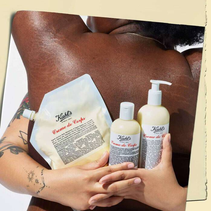 2 people embracing. 1 person’s hands hold Kiehl’s Creme De Corps lotion in bottle, and refillable form. 
