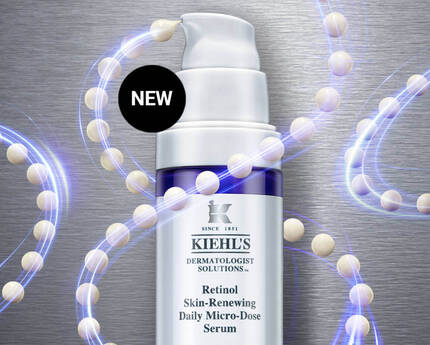 A bottle of Kiehl's Retinol Skin-Renewing Daily Micro-Dose Serum, featuring a sleek design with a purple and white color scheme, set against a metallic background with decorative swirling lines and white beads. The label indicates the product is new.