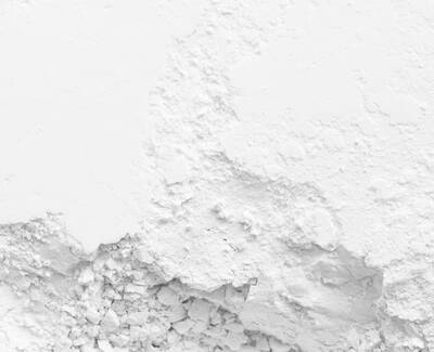 Close-up of a textured white surface with fine powdery and rough areas, creating a contrast between smooth and grainy textures.