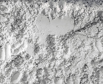A textured surface made of fine, white powder, with footprints and patterns visible throughout.