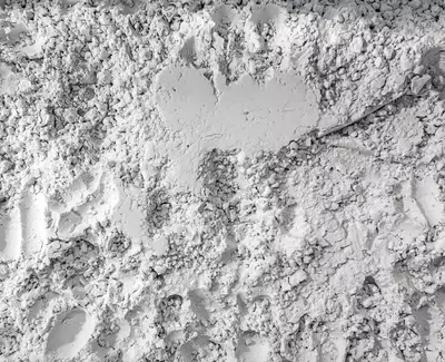 A textured surface made of fine, white powder, with footprints and patterns visible throughout.