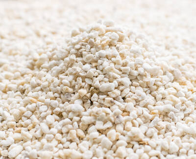 A close-up of a pile of small white and beige pebbles or granules arranged on a flat surface.