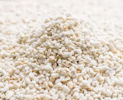 A close-up of a pile of small white and beige pebbles or granules arranged on a flat surface.