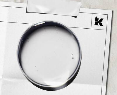 Close-up image of a transparent crystal fragment, showcasing intricate internal textures and patterns, set against a soft, blurred background.