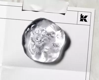 Close-up of a clear, textured skincare gel droplet on a laboratory document, featuring Kiehl’s iconic "K" logo, illustrating the brand's clinical approach to formula development. 