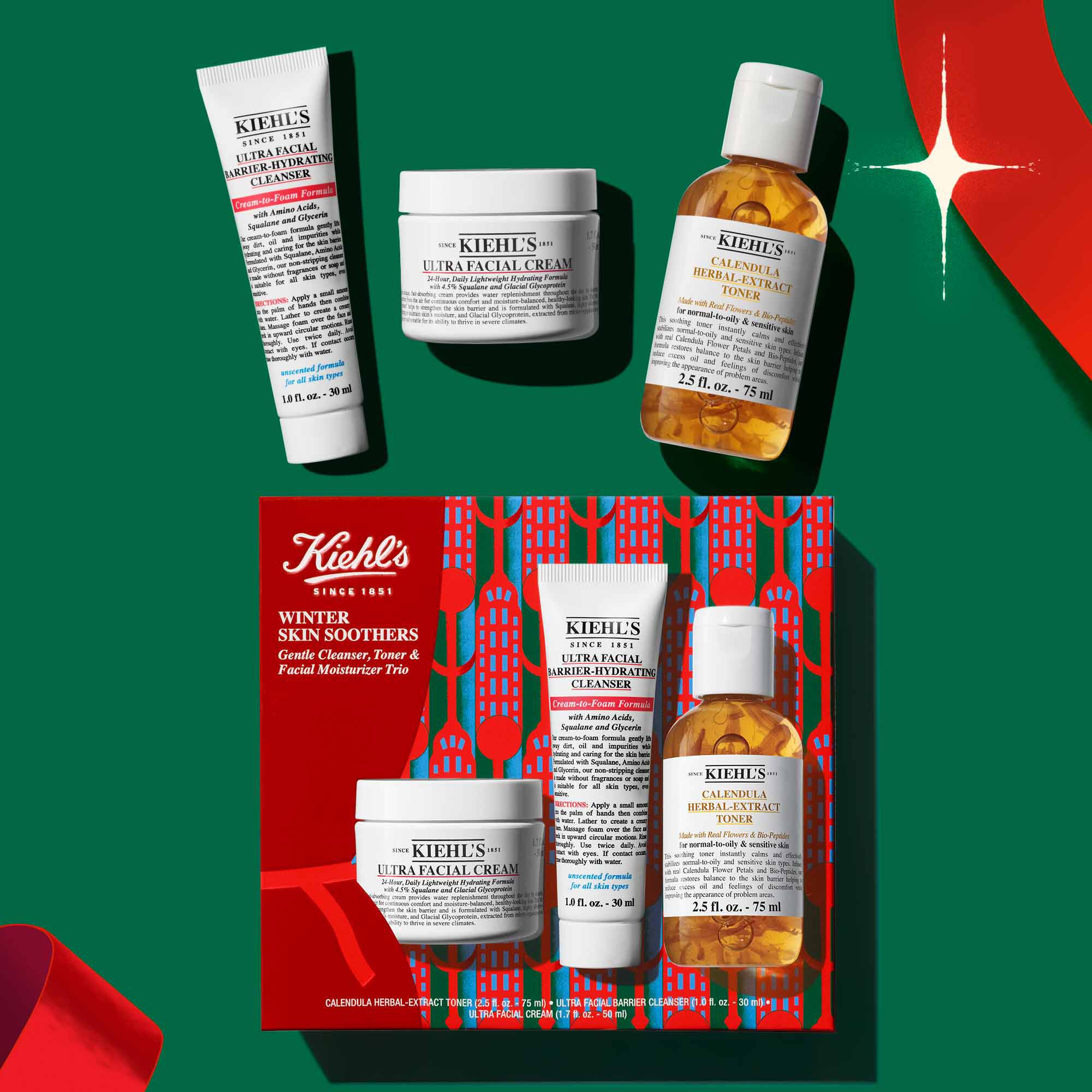Kiehl's Winter Skin Soothers holiday gift set featuring Ultra Facial Barrier-Hydrating Cleanser, Ultra Facial Cream, and Calendula Herbal-Extract Toner against a festive green background.