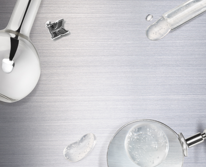 A flat lay of laboratory equipment, including beakers, a pipette, petri dishes, and glass droplets, arranged on a metallic surface.