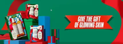 Kiehl’s Christmas gift sets arranged against a festive green and red background, with the message Give the gift of glowing skin.
