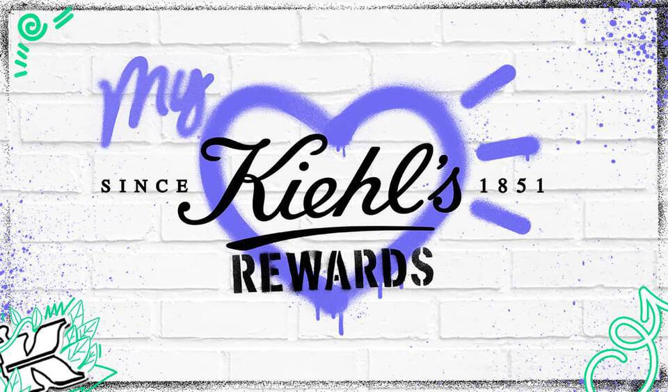 A graphic promoting Kiehl's Rewards, featuring a heart design and playful graffiti elements on a brick wall background.
